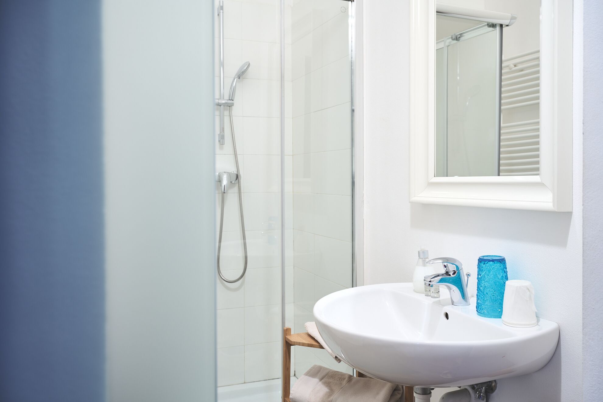 A bathroom with a glass shower enclosure, a white sink, and a mirror above it.