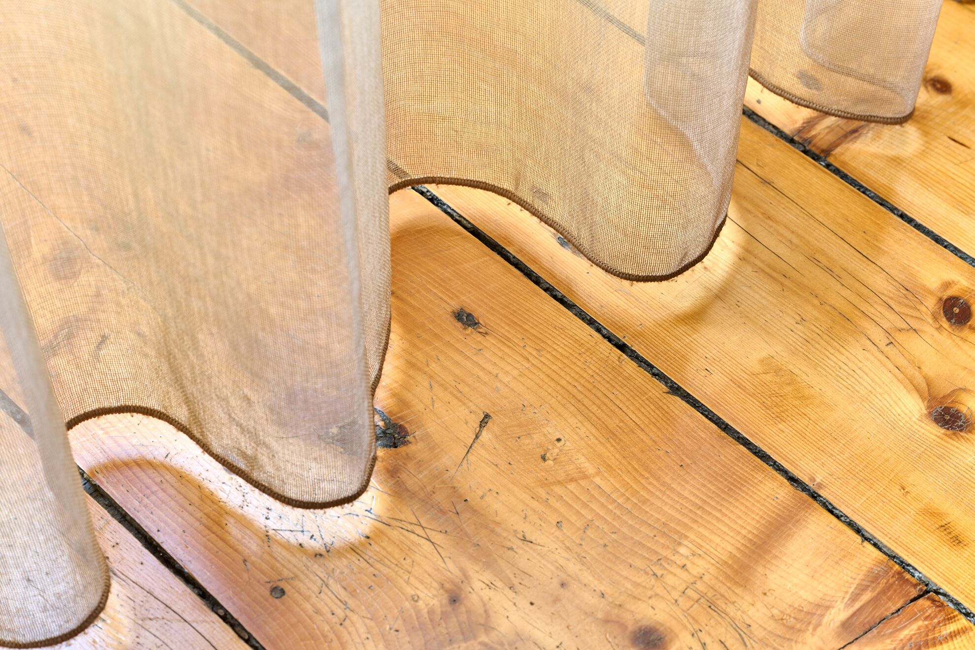 Gros plan d’un plancher en bois présentant des signes d’usure, notamment des rayures et des marques d’éraflures.