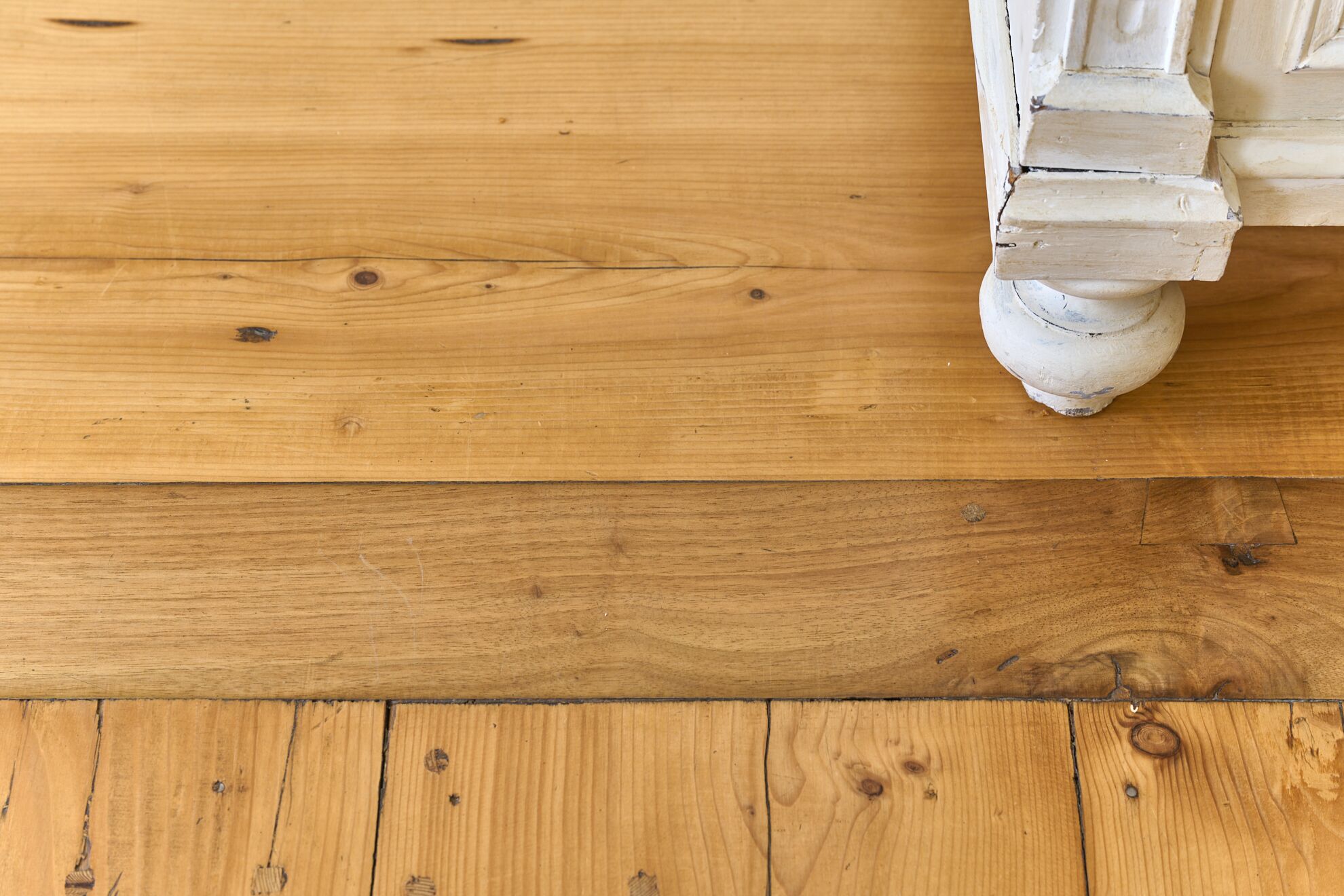 A wooden floor with a white, distressed column base.