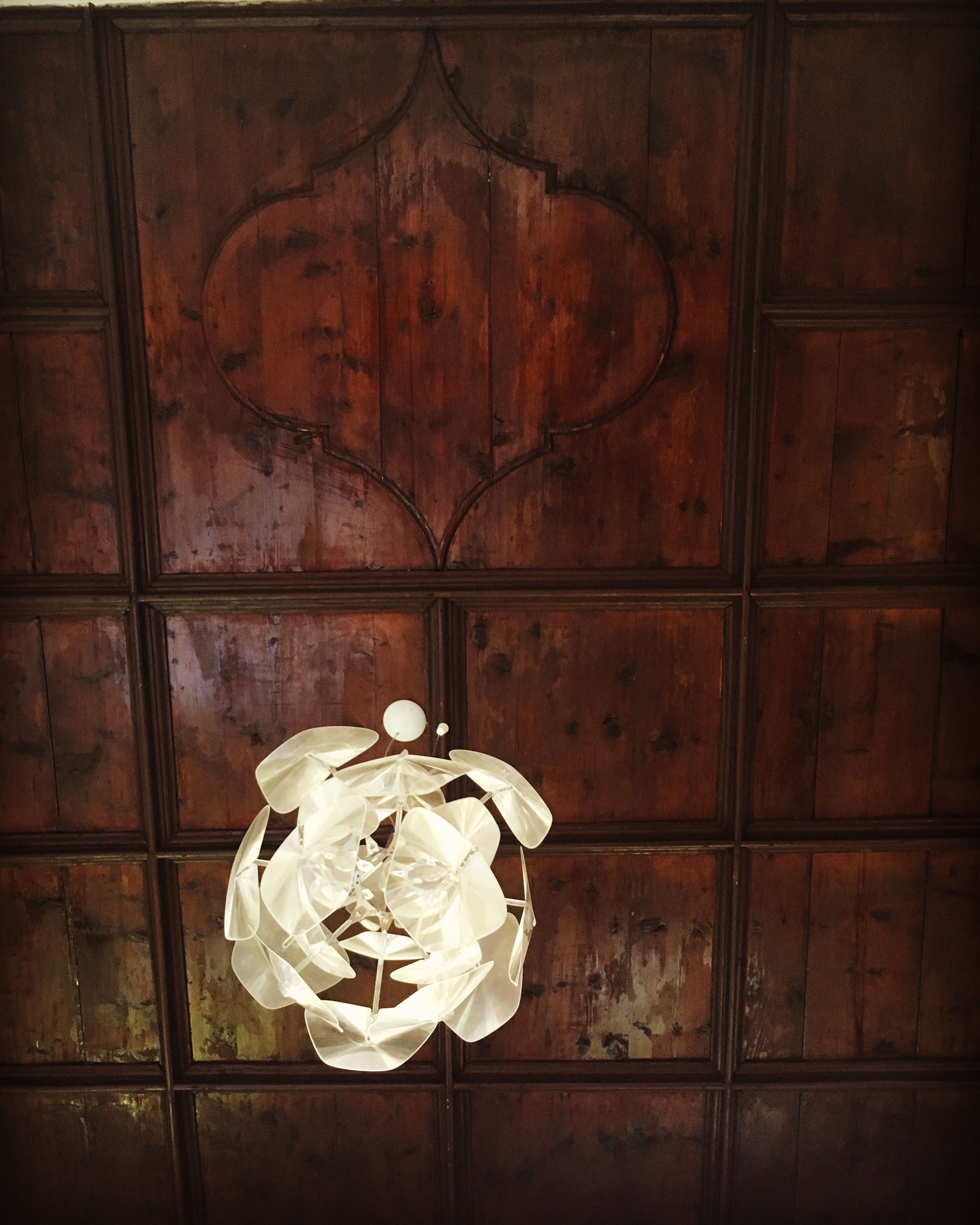 Pared de paneles de madera con una lámpara decorativa en el techo.