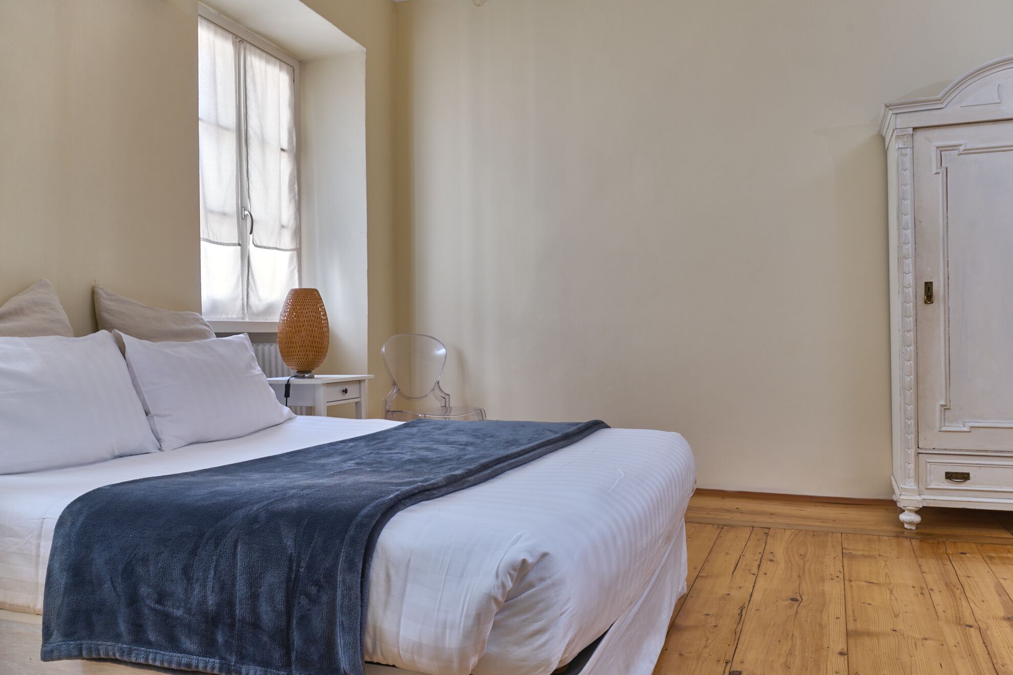 Een slaapkamer met een bed, nachtkastje, lamp en garderobe.
