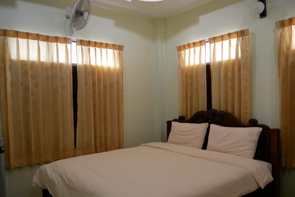 A bedroom with a bed, curtains, a ceiling fan, and a wall-mounted light fixture.