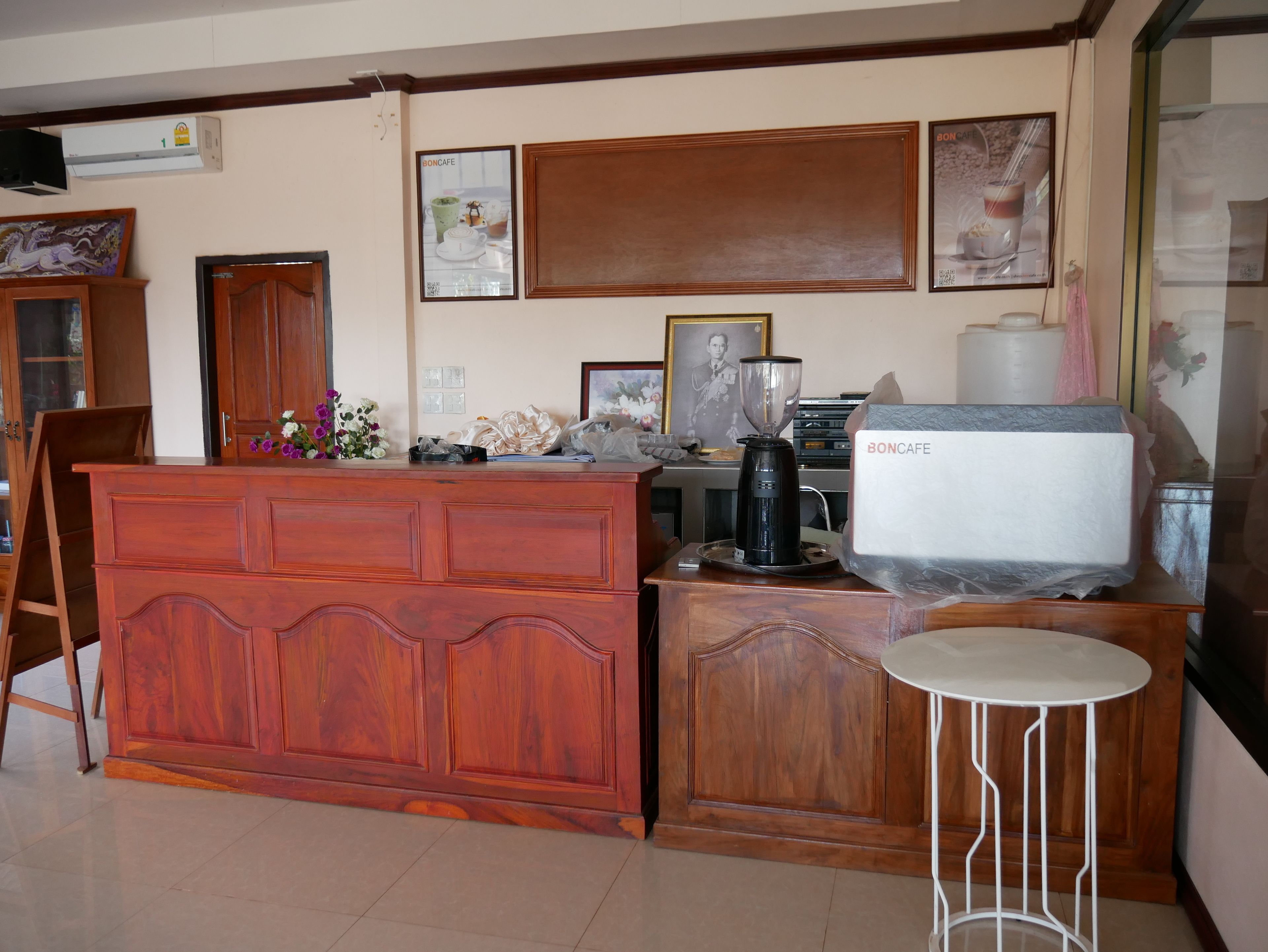 A kitchen with wooden cabinetry, a coffee maker, and a small white table.