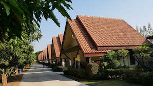 A row of traditional-style buildings with sloped roofs and a paved pathway leading through them. - Suanluang Garden View Resort (Nong Khai)