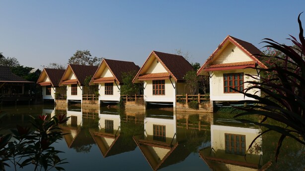 A row of traditional houses with tiled roofs, reflecting in calm water. - Suanluang Garden View Resort (Nong Khai)