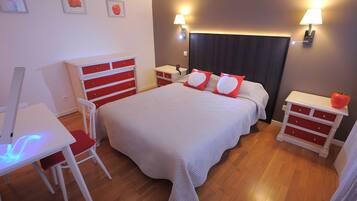 A neatly arranged bedroom with a bed, bedside tables, a desk, and a chair.
