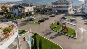 A parking lot with multiple cars, a playground with a slide, and a fountain.