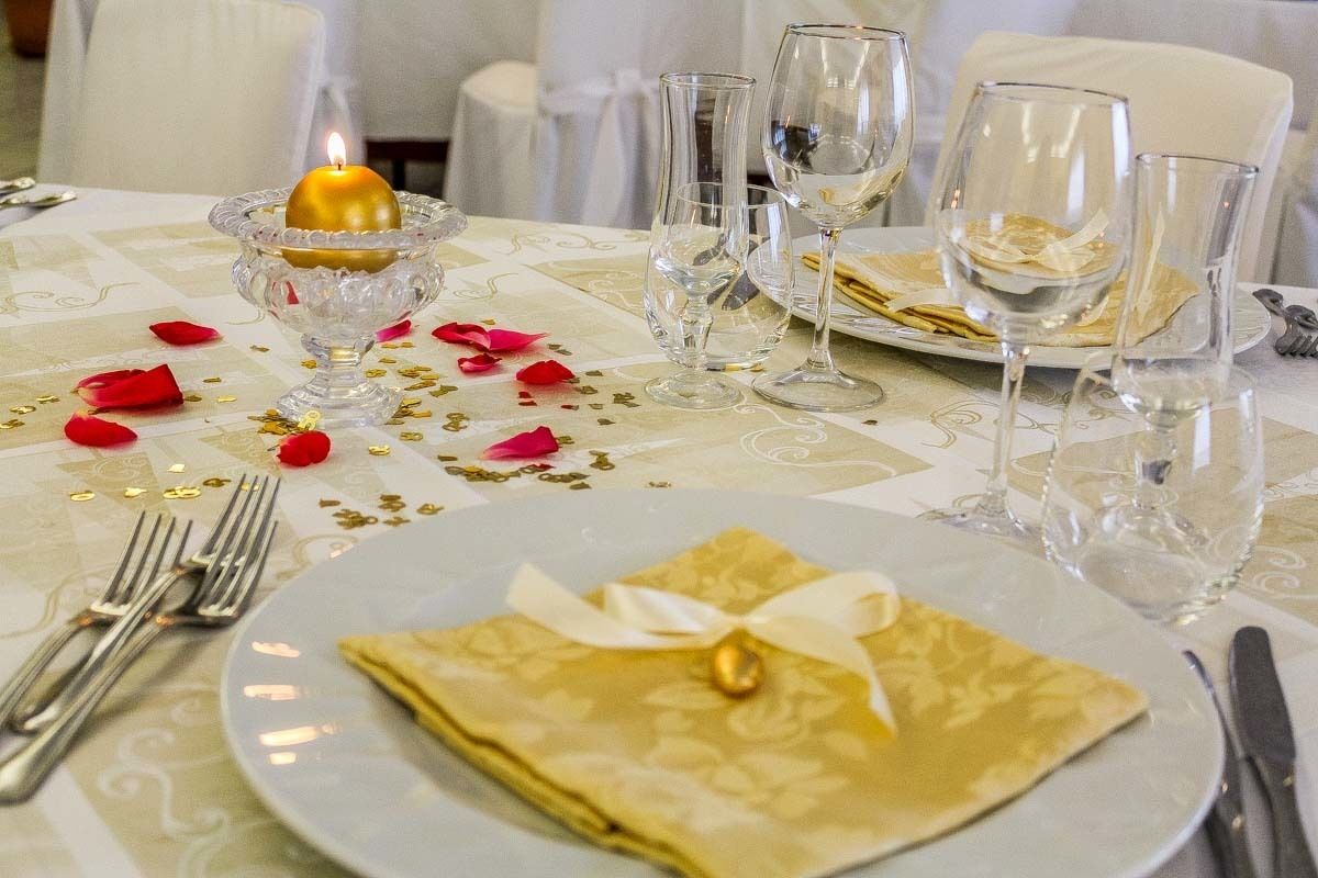 A table set for a meal with a lit candle, empty wine glasses, and a folded napkin with a bow.