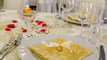 A table set for a meal with a lit candle, empty wine glasses, and a folded napkin with a bow.