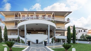 A hotel with a curved entrance, multiple balconies, and a central staircase.