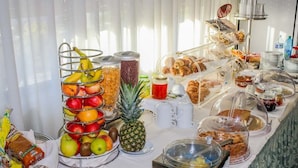 A buffet with various food items including fruits, pastries, and beverages.