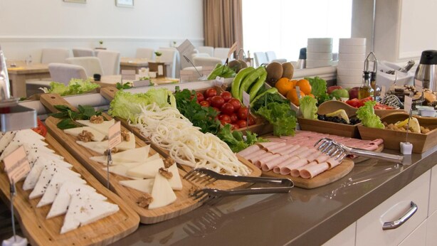 Un bufé con diversos quesos, carnes, frutas y verduras.