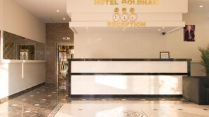 Zona de recepción de un hotel con mostrador, un reloj y un cuadro en la pared.