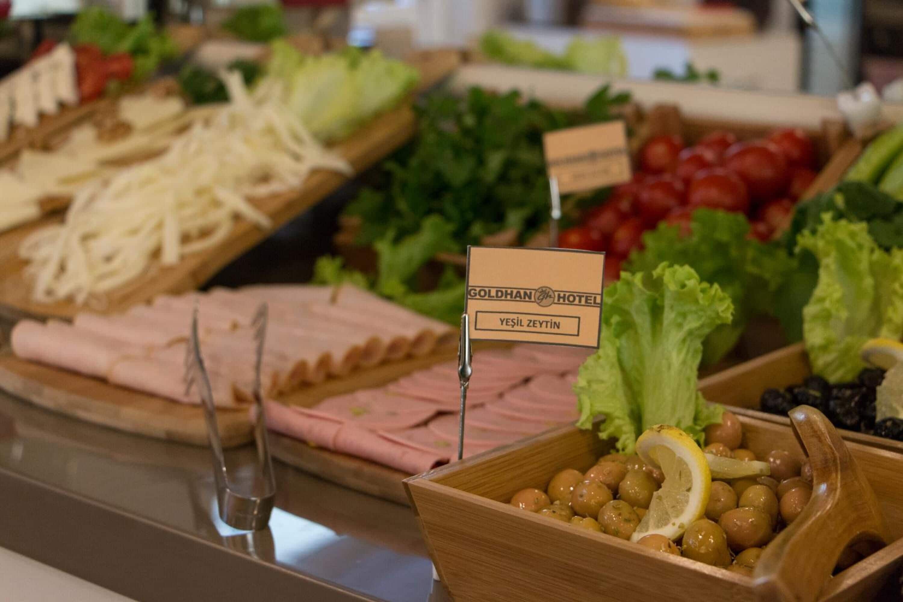 Un bufé con diversas opciones de comida, incluyendo queso, carnes y verduras.