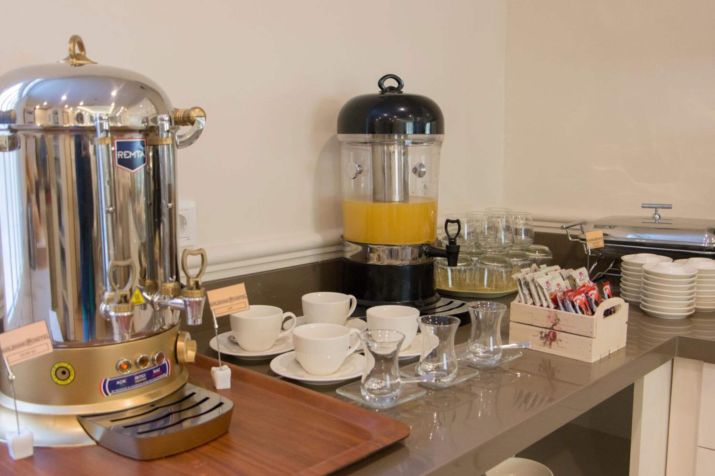 A buffet setup with a coffee maker, tea maker, and various cups and saucers.