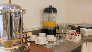 A buffet setup with a coffee maker, tea maker, and various cups and saucers.