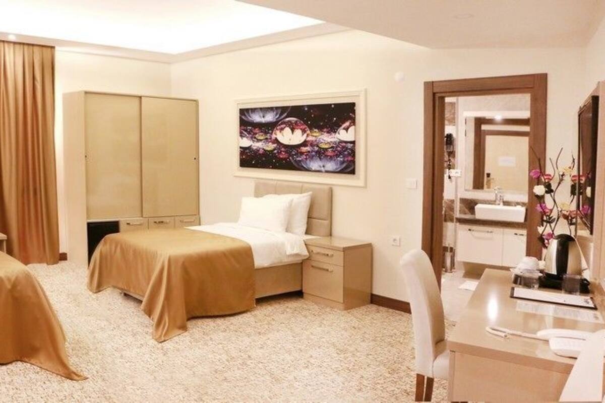 Habitación de hotel con dos camas, un escritorio, una silla, un armario y un cuadro en la pared.