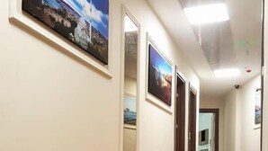 Un pasillo con alfombra estampada, cuadros en las paredes y puertas que dan a otras habitaciones.
