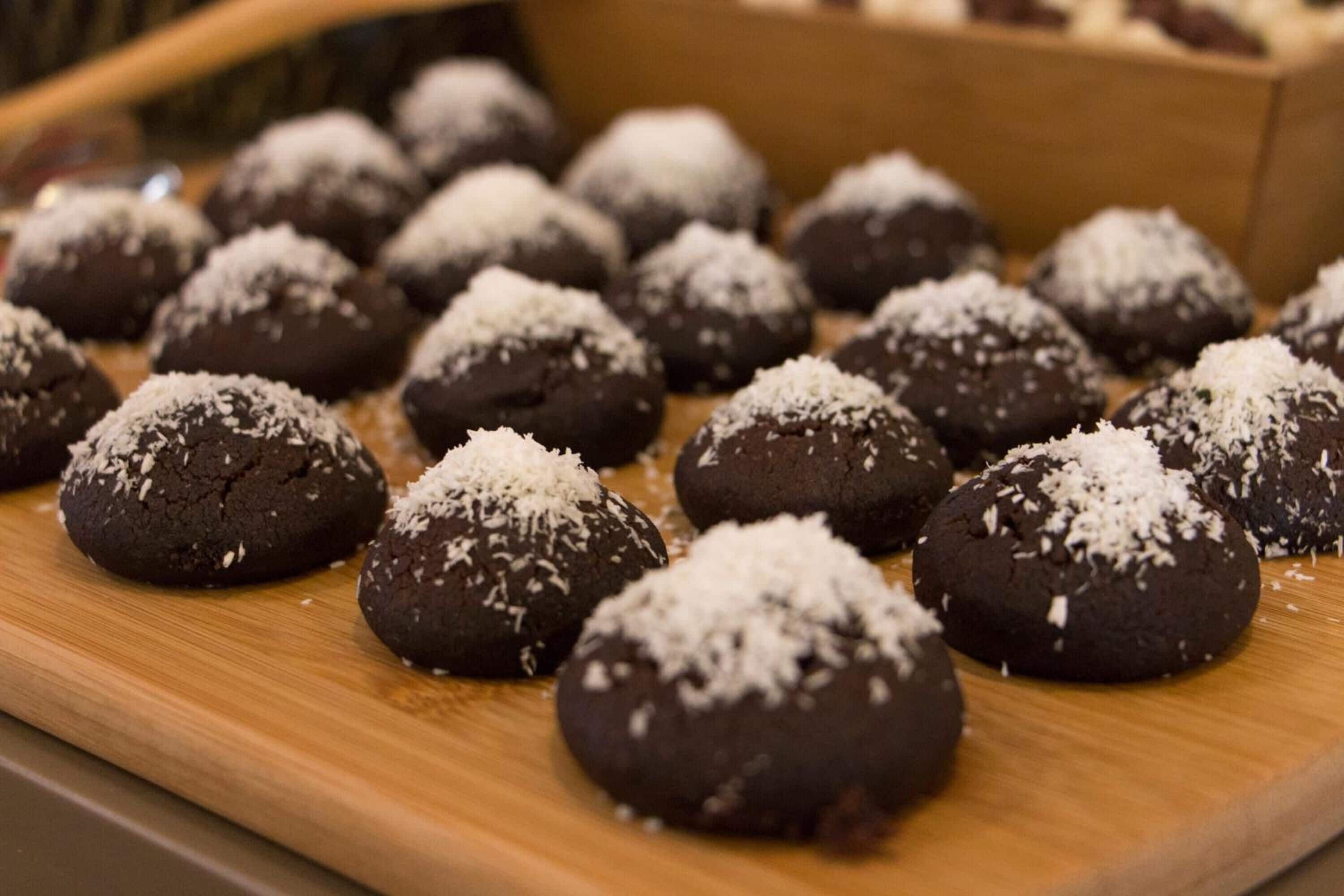 A tray of chocolate cookies with coconut shavings.