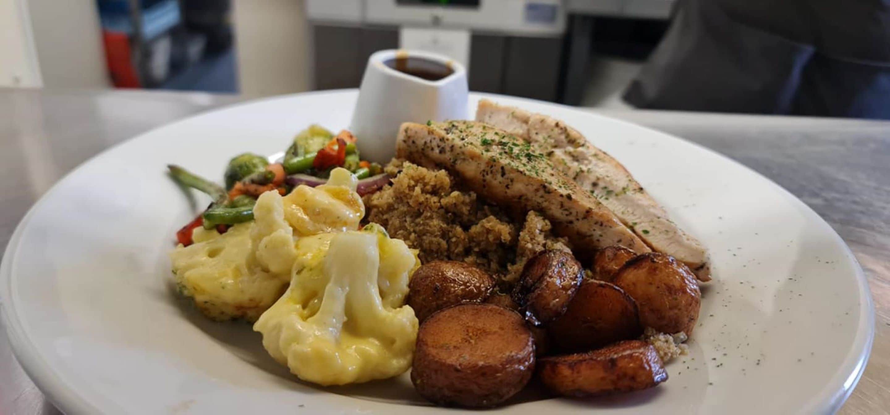 Un plato con puré de papas, vegetales asados y un trozo de carne.