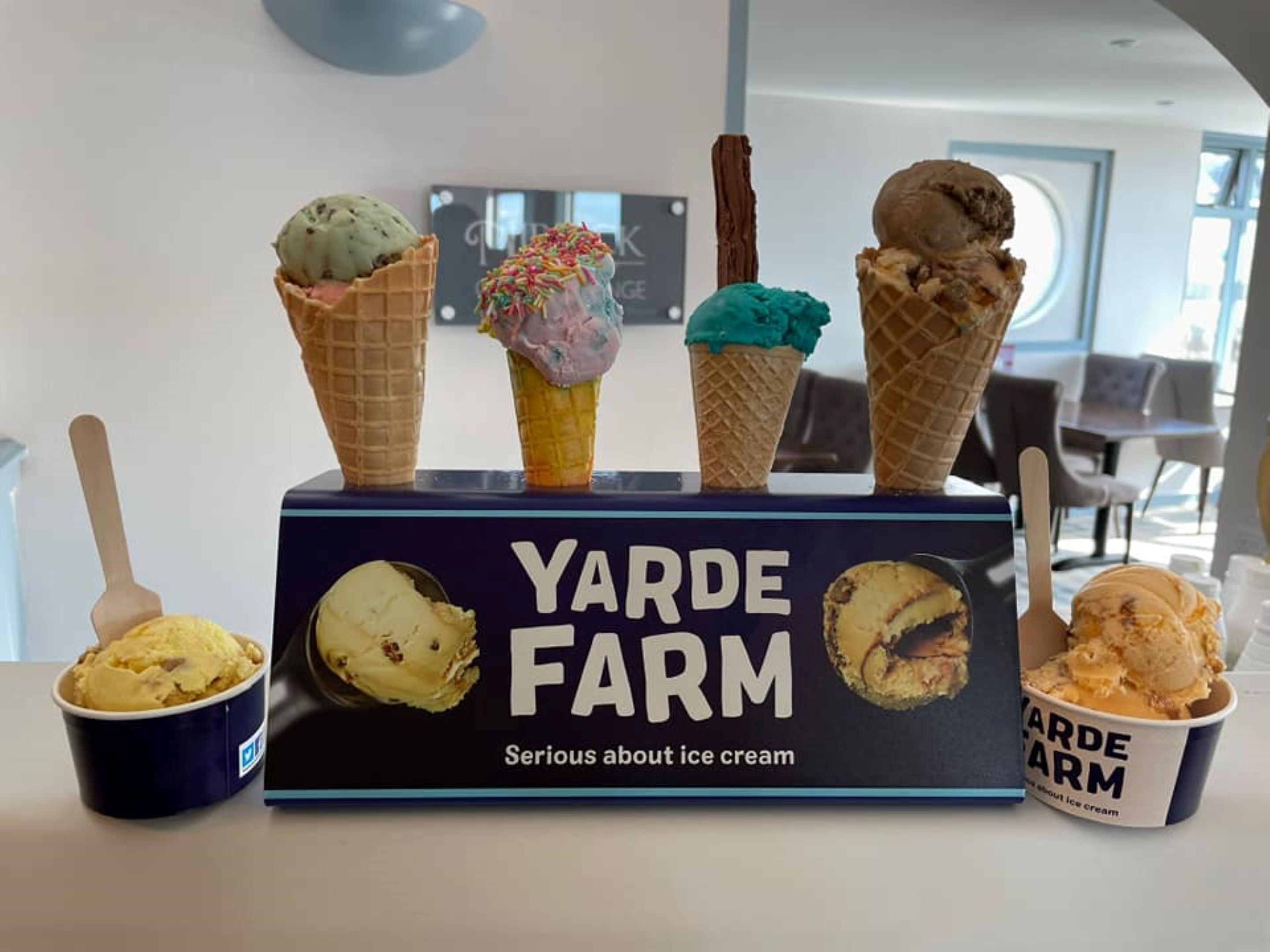 Presentación de cucuruchos y tarrinas de helado en Yarde Farm, con un cartel que dice 'Nos tomamos el helado en serio'.