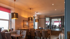 A restaurant with wooden tables and chairs, hanging pendant lights, and a framed picture on the wall. - Golf View Hotel (Lossiemouth)