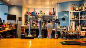 A bar area with multiple beer taps, a variety of liquor bottles, and a sign indicating a hotel. - Golf View Hotel (Lossiemouth)