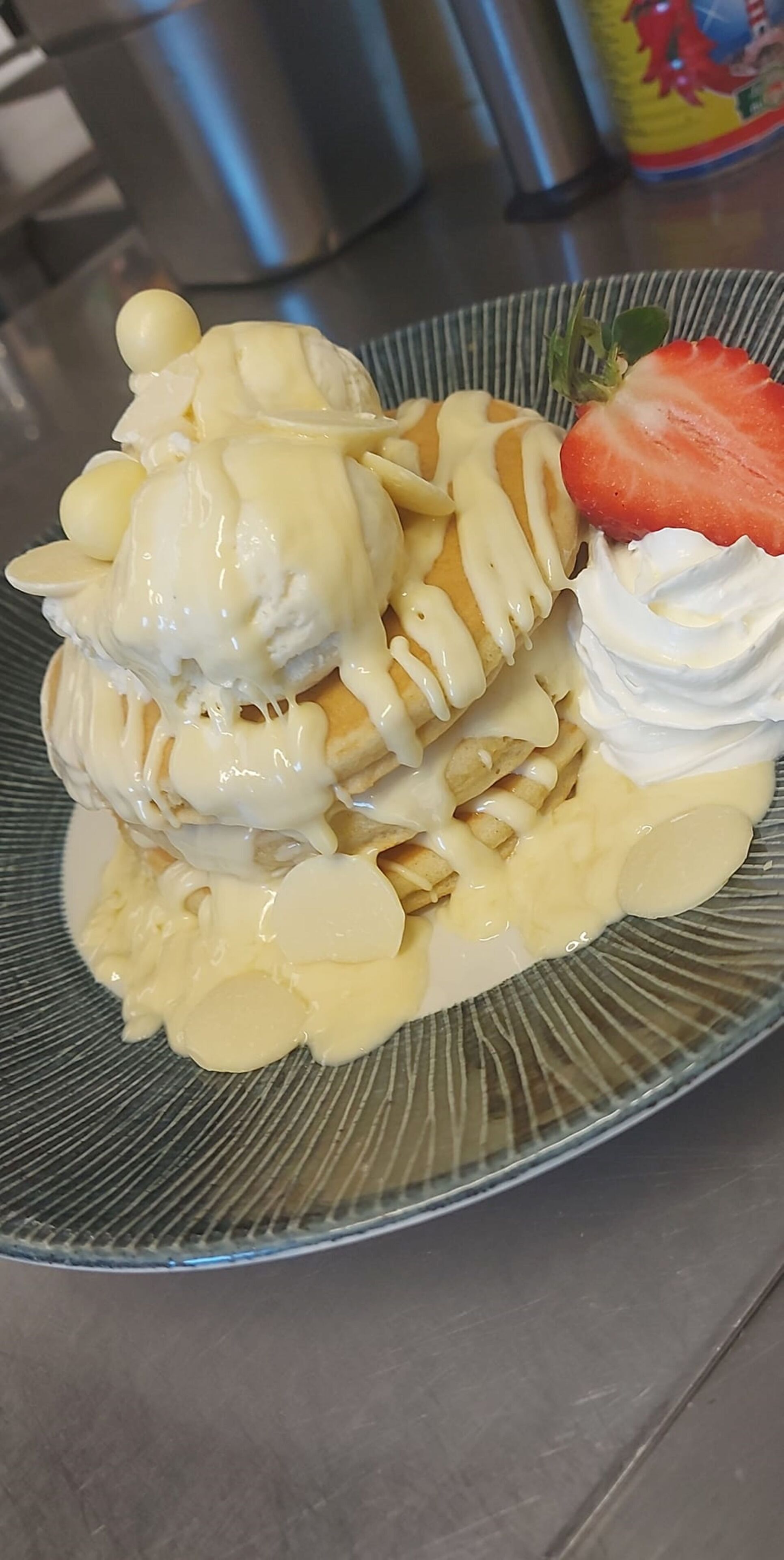 A dessert plate with a stack of pancakes, whipped cream, and a strawberry.
