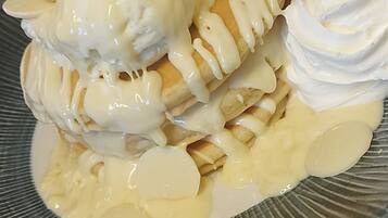 A dessert plate with a stack of pancakes, whipped cream, and a strawberry.
