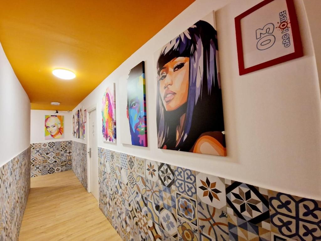 Un pasillo con paredes y techo con diseños, que incluye obras de arte y una puerta con un número.