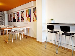 A modern interior with a wooden floor, white and black chairs, and a wall adorned with colorful paintings.