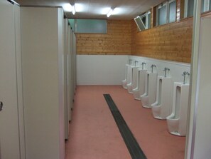 A row of white urinals in a restroom with a wooden wall and a pink floor.