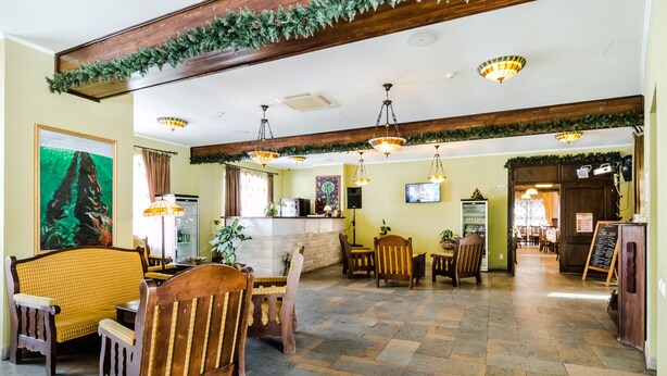 A spacious lobby with wooden furniture, a reception desk, and a television screen. - Ezio Brasov (Sacele)