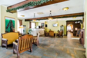 A spacious lobby with wooden furniture, a reception desk, and a television screen. - Ezio Brasov (Sacele)