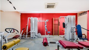 A gym with various exercise machines, benches, and a red wall. - Ezio Brasov (Sacele)