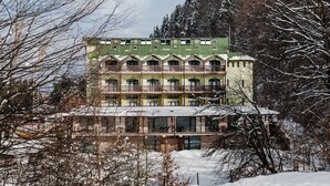 A multi-story hotel with balconies, surrounded by snow-covered trees. - Ezio Brasov (Sacele)