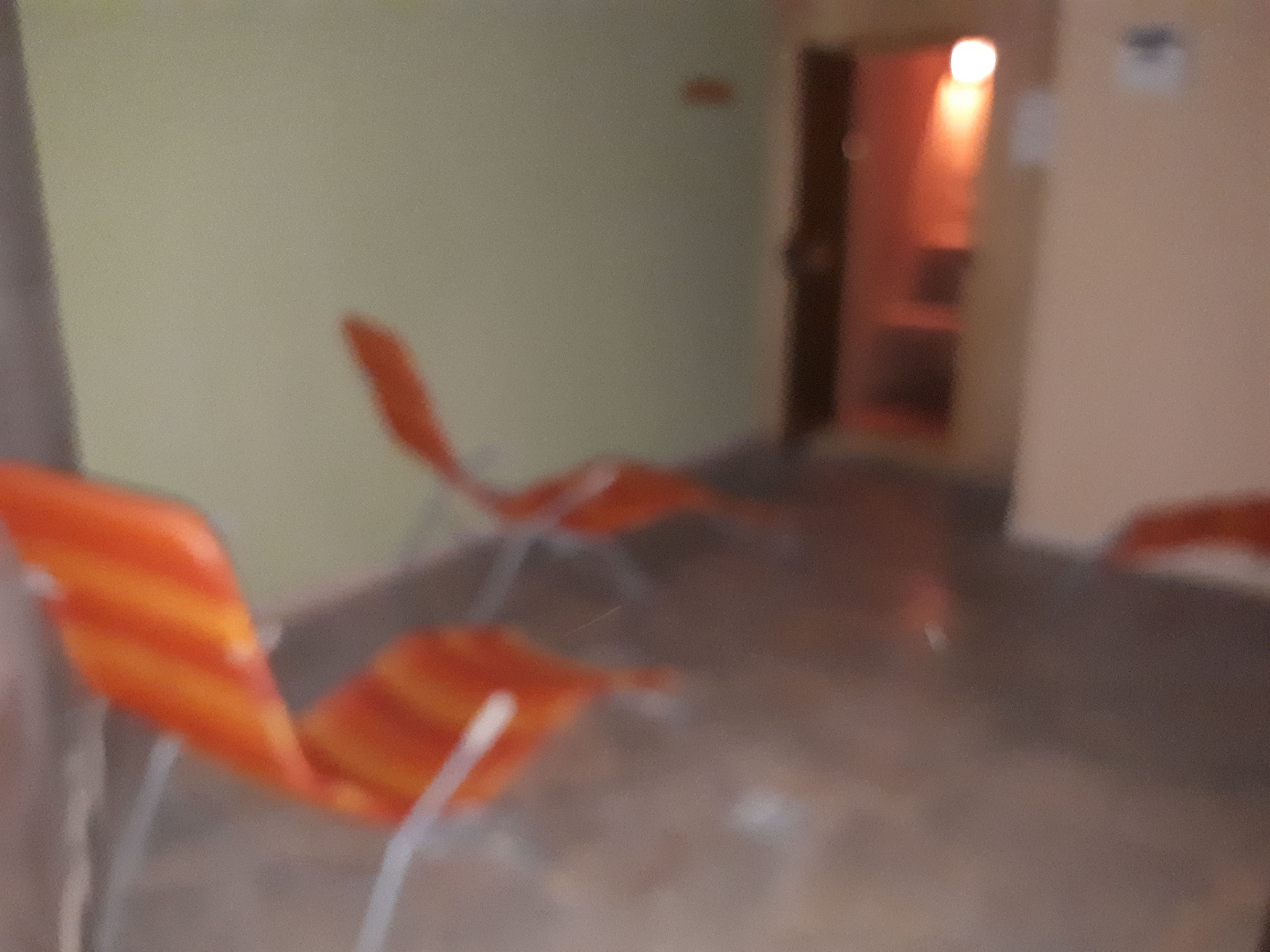 Una habitación con una mesa grande y redonda, y varias sillas color naranja.