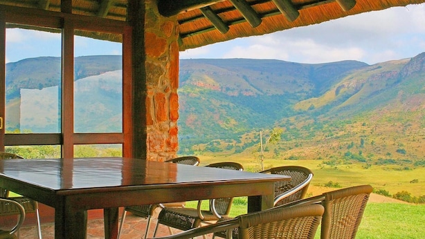 A dining area with a table and chairs, large windows, and a view of mountains.