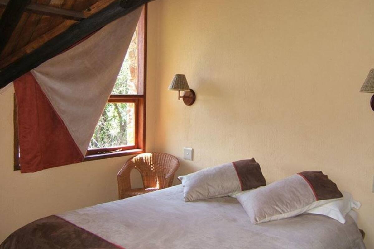 Ein Schlafzimmer mit einem Bett, zwei Wandlampen, einem Fenster mit Blick und einem Stuhl.