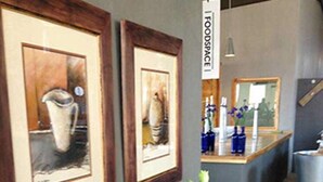 A hallway with a wooden bench, framed artwork on the wall, and a counter with bottles and a mirror.