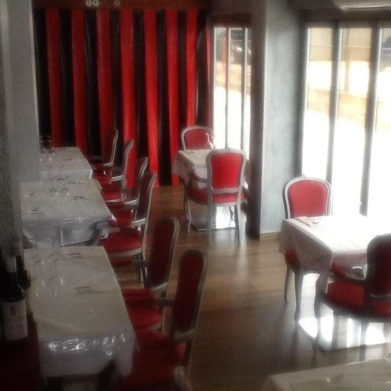 Un restaurante con mesas y sillas, una cortina a rayas y vistas a través del ventanal.