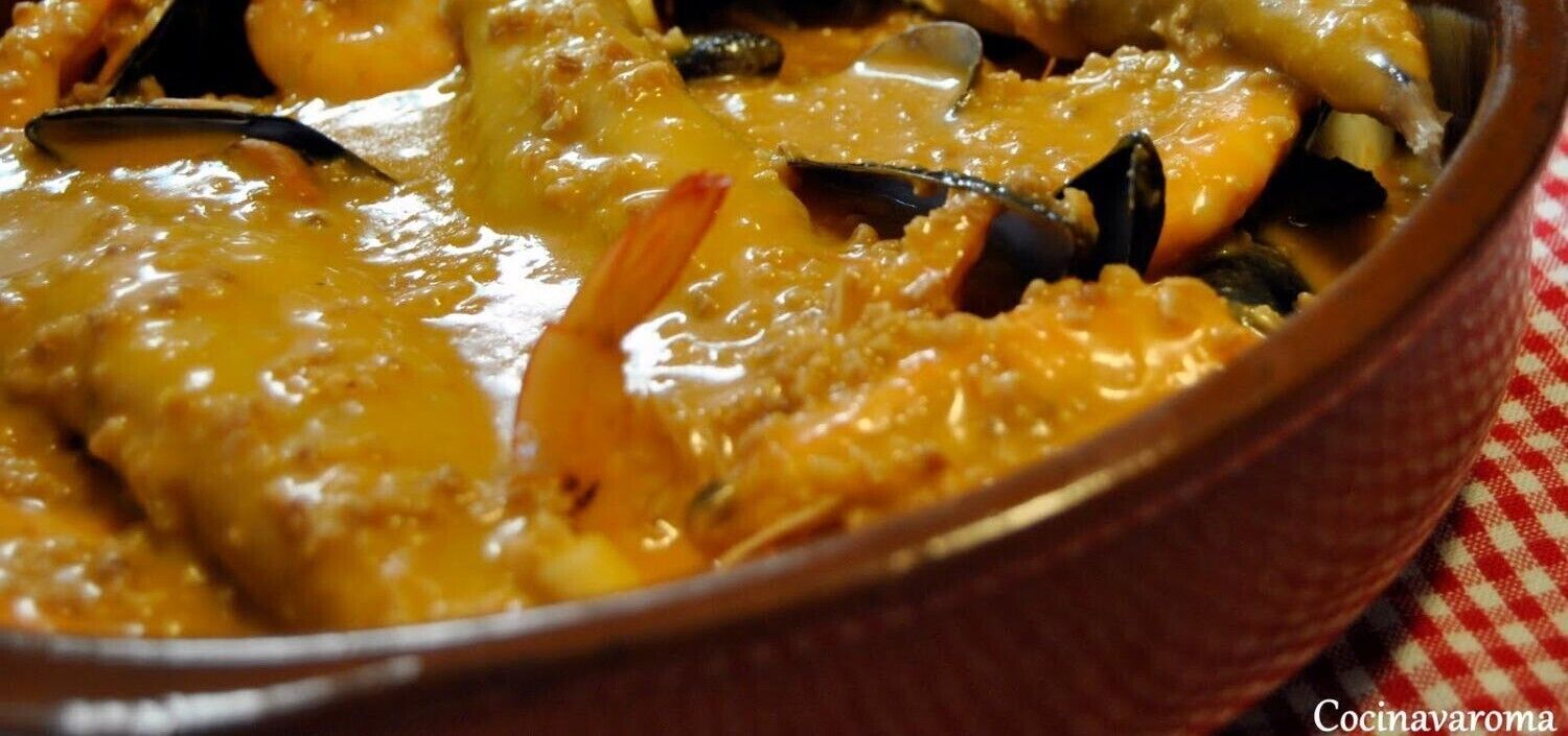 A close-up of a seafood dish with mussels and shrimp in a creamy sauce, served in a ceramic dish.
