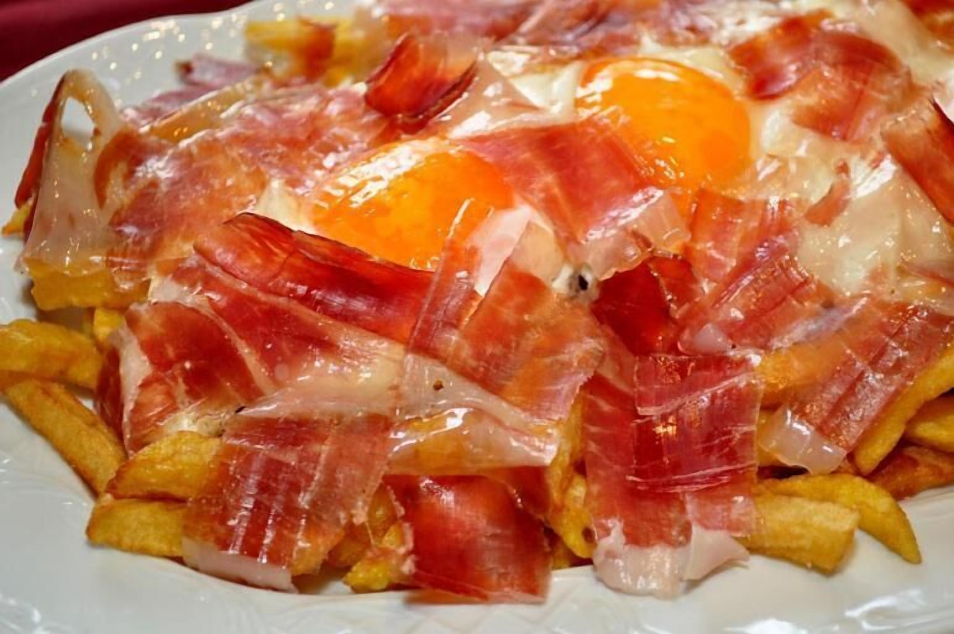 Un plato de comida con huevos, tocino y papas fritas.