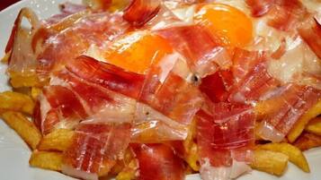 Un plato de comida con huevos, tocino y papas fritas.
