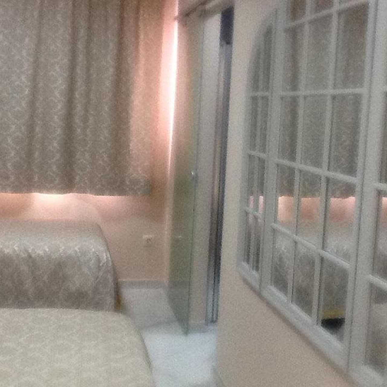 Une chambre d’hôtel avec deux lits, une grande fenêtre et une porte coulissante.