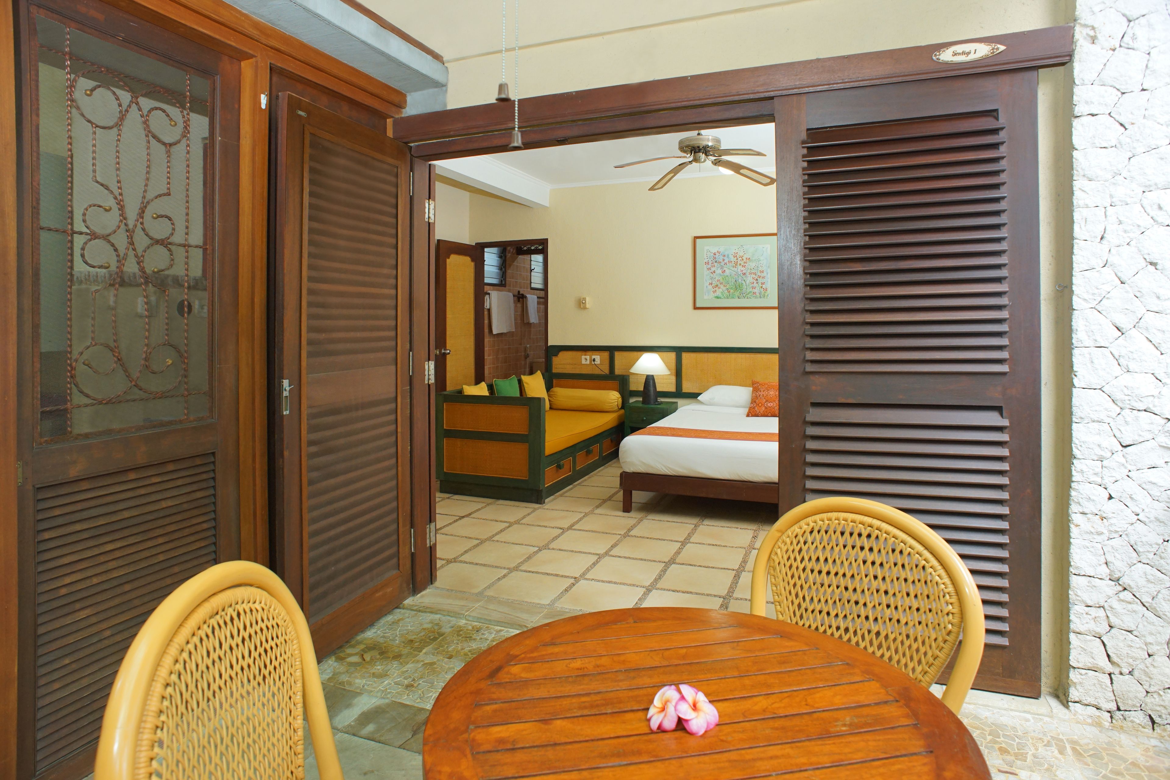 A hotel room with a bed, a sofa, a dining table, and a chair.