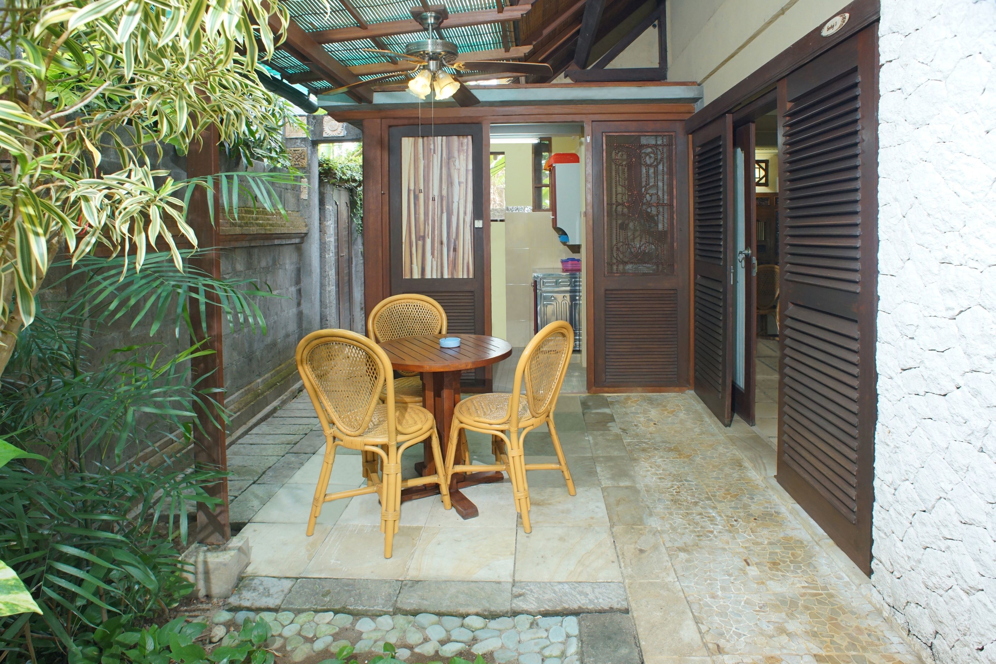 Un patio con una mesa, sillas, un ventilador de techo y piso de baldosas de piedra.