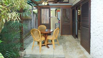 Un patio con una mesa, sillas, un ventilador de techo y piso de baldosas de piedra.
