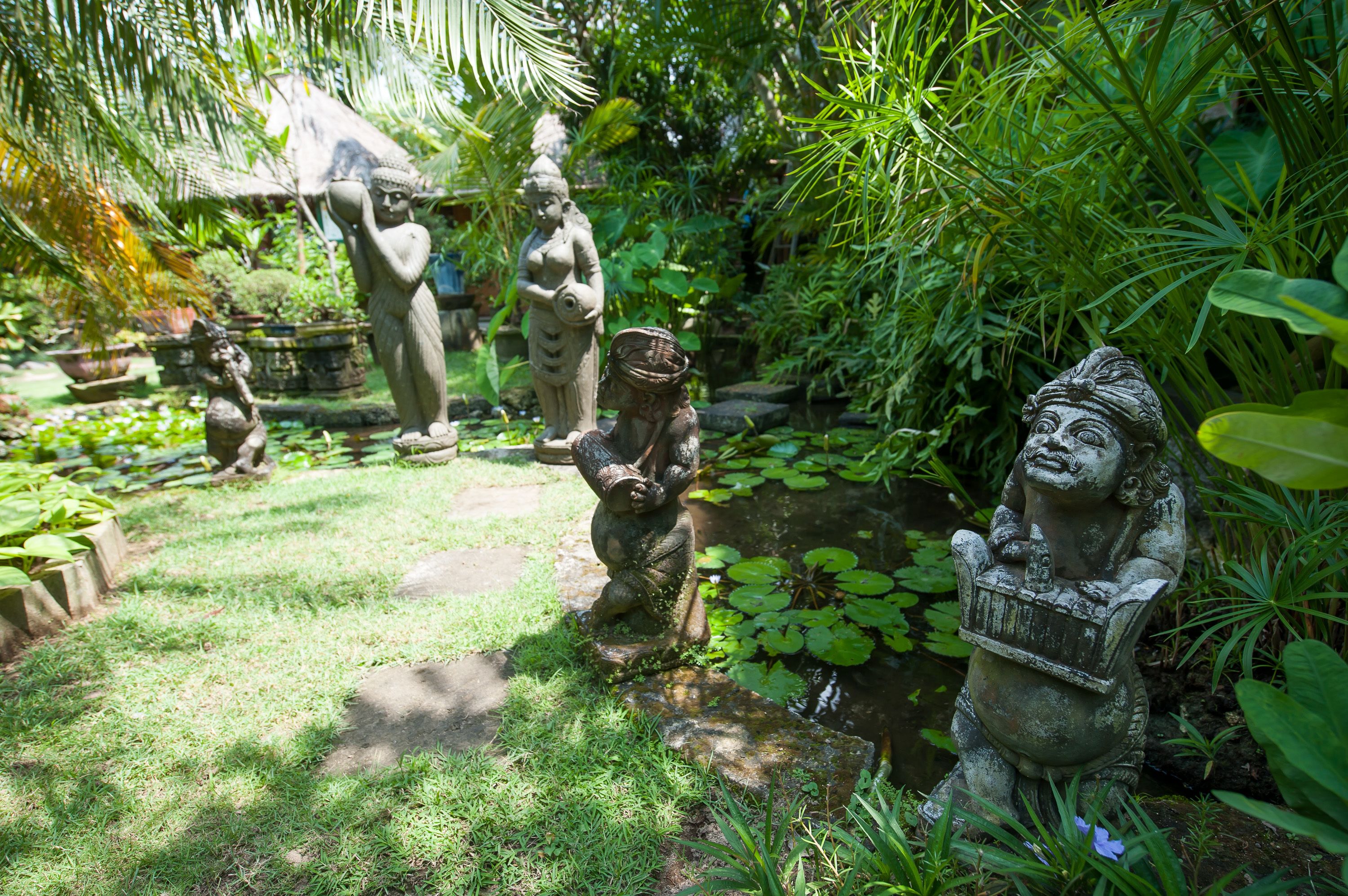 Un jardín con estatuas y abundante vegetación.