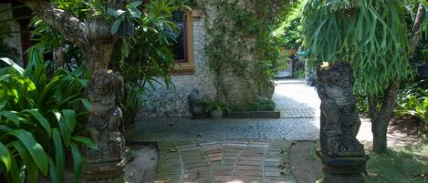 Un camino de piedra que conduce a una casa tradicional con una ventana y un muro de piedra.